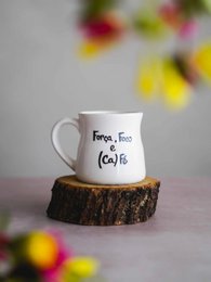  White ceramic mug with the text "Força, foco e (ca)fé" printed on it, standing on a wooden log.