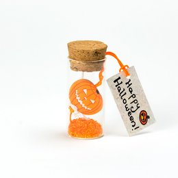 A small glass bottle filled with orange slices, sealed with a cork stopper. The bottle has a tag attached that reads "Happy Halloween".