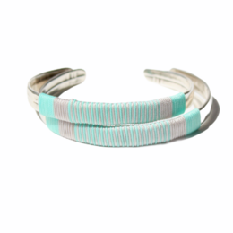 A mint-colored bangle bracelet made of silver and gold-toned metal with a textured, layered design.