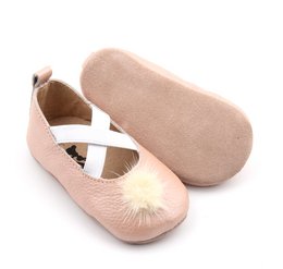 Powder pink leather ballerina shoes with criss-cross straps and a pom-pom accent, suitable for babies in sizes T0 to T4.