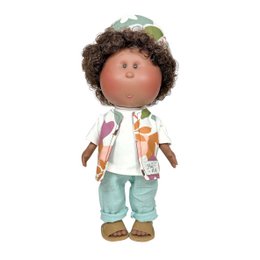  A plush baby doll with curly brown hair, wearing a white shirt, mint green pants, and brown sandals. The doll has a friendly, smiling expression.