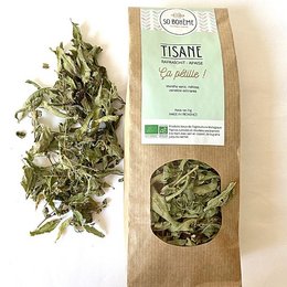 Organic digestive herbal tea with green leaves and stems, packaged in a paper bag. The tea appears to be a blend of various herbs and leaves, likely intended to aid digestion.