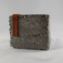 A raw concrete design table lamp with an industrial cement base in multiple colors, including black and cognac. The lamp has a unique, textured concrete design and a simple, minimalist style.