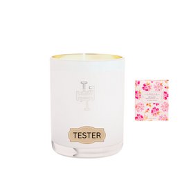 A tall, round white candle with a pink base and a gold-colored lid. The candle has the word "tester" printed on it in a stylized font.