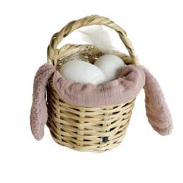  Woven rattan basket with dusty rose-colored plush rabbit ears and three white eggs inside.