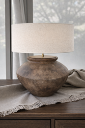  A rustic ceramic table lamp with an earthy, textured finish. The lamp has a rounded, bulbous shape and a brass-colored lamp base.