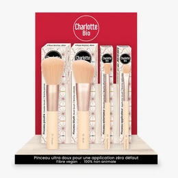 A set of makeup brushes in a display stand. The brushes have white handles and pink bristles. The display stand is red with the Charlotte Tilbury logo.