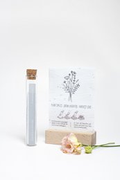 Wildflower seeds in a glass vial, with a label that says "100 moments of happiness - moments of happiness #field flowers (seeds in growing paper)". The seeds are accompanied by a wooden sign with the text "Grow your own wildflowers".