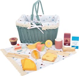 A wicker picnic basket filled with a variety of toy food items, including sandwiches, fruits, and other picnic-themed accessories. The basket has a polka dot lining and handles.