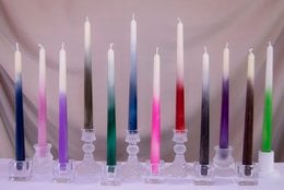 Tall, ombre-colored beeswax taper candles in a variety of vibrant hues including pink, purple, blue, and green. The candles have a unique gradient effect that transitions between the different colors.