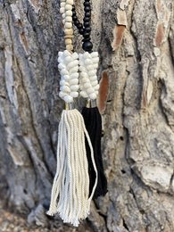  Wooden pendant necklace with shells, tassels, and beads in black and white colors.
