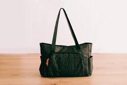 Large, quilted diaper bag in olive green with multiple pockets and compartments for convenient storage and organization.