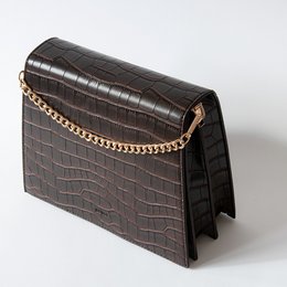 A croc-embossed brown leather handbag with a gold chain strap.