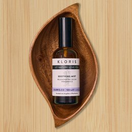  Soothing mist aromatherapy sleep spray in a glass bottle with a wooden leaf-shaped tray. The spray is labeled "Kloris" and contains natural ingredients to promote relaxation and sleep.