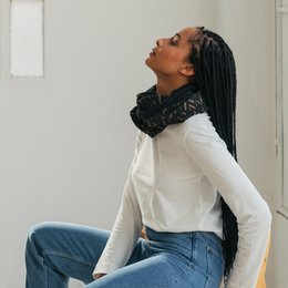 Infinity scarf with a black and gold leaf pattern design. Made of soft, lightweight material for comfortable wear.