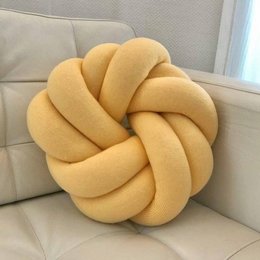 Decorative knot-shaped cushion in a sunny yellow color, made of soft, plush material. Ideal for adding a cozy, textural accent to any living space.