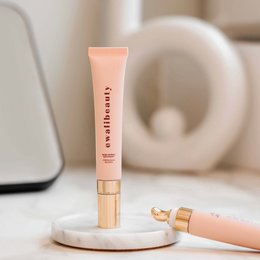 A peach-colored eye cream in a tube with a gold cap. The cream has a smooth, creamy texture and is designed to hydrate and rejuvenate the delicate eye area.