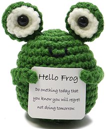  A green crocheted frog plush toy with large eyes and a friendly expression. The frog appears to be a push or pull toy, with a round body and limbs that could be used for movement.