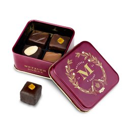  A small, rectangular tin containing assorted gourmet praline chocolates in a deep red color with a decorative floral design.