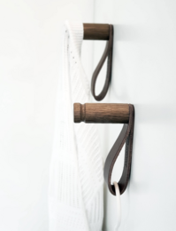 Dark brown coat rack hooks made of wood and leather, suitable for hanging coats, bags, or other items.