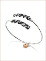  Burnished gold-tone cuff bracelet with intricate floral design and dangling charm.