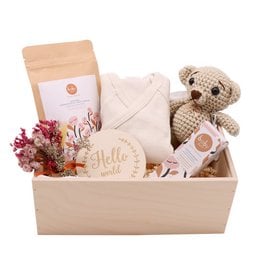 Wooden gift box containing baby fragrance, plush toy, and other baby care items. Neutral colors and natural materials.
