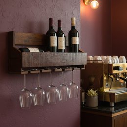 Rustic wooden wine rack with open shelves for storing and displaying wine bottles.