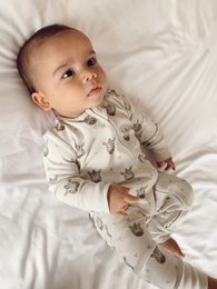 Soft, cozy zebra-patterned sleepsuit for babies, available in sizes 0-3 months to 12-18 months.