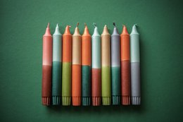 Colorful, tapered candles in a variety of pastel shades, including mint green, light blue, and coral. The candles appear to be part of a "Dippy Winter Collection" and are displayed on a woven basket or tray.