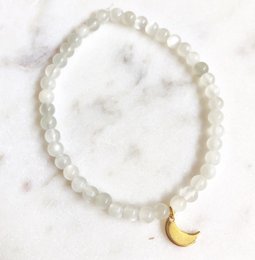 A delicate bracelet featuring a strand of white moonstone beads with a small crescent moon charm. The bracelet has a simple, elegant design that would complement a variety of outfits.