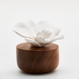 White ceramic orchid-shaped fragrance diffuser on a wooden base, originating from Nepal.