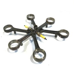 Upcycled motorcycle parts coaster in the shape of a drone, featuring 6 or 4 wrench-shaped holders for drinks. Made from repurposed materials, this unique coaster has an industrial, mechanical design.