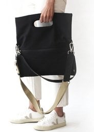 Black tote bag with leather handles and detachable strap. Minimalist design suitable for everyday use.