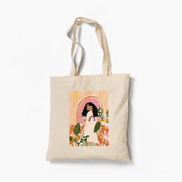 Organic cotton tote bag featuring a colorful illustration of a woman with long dark hair surrounded by flowers and leaves.