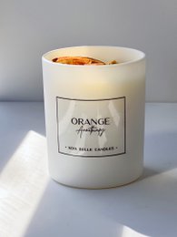 Orange aromatherapy candle with a warm, citrusy scent. Made of natural wax and essential oils. Cylindrical shape with a simple white label.