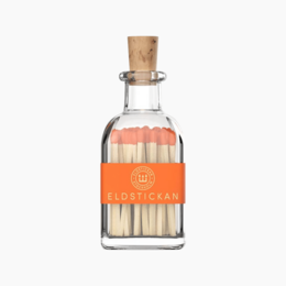 Small glass bottle with orange label and wooden cork containing matches.