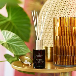 Amber-colored reed diffuser with a glass container and gold accents. Includes essential oils for home fragrance.