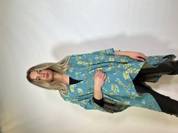 Teal and yellow floral print poncho with long sleeves and asymmetric hem. Made of lightweight, flowing fabric. Suitable for casual or formal wear.