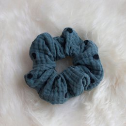 Teal blue polka dot scrunchie hair accessory made of soft, textured fabric.