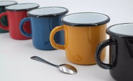 Enamel mugs in various colors including milk, aquamarine, light green, mustard, dark turquoise, and valentine. The mugs have a vintage, fair trade aesthetic and are made of durable enamel material.