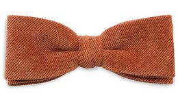 A terracotta-colored corduroy bow tie with a classic style and texture.