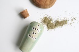 A ceramic vase holding a bouquet of colorful dried flowers, including red, yellow, and green floral elements. The vase has a textured, earthy appearance.