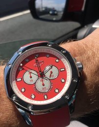 Stainless steel chronograph watch with a red dial, 10 ATM water resistance, and a red leather strap.