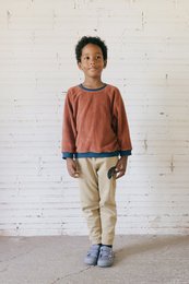 Beige kids sweatpants with a rust-colored long-sleeved top. The outfit features a simple, casual style suitable for everyday wear.