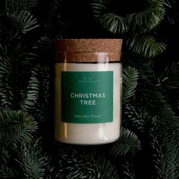 Tall, round, white candle in a glass jar with a cork lid. The label on the jar reads "Christmas Tree" in green text.