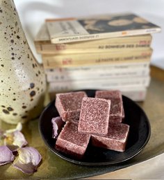 A rectangular amber-colored perfume block with a textured surface, presented on a dark plate alongside other decorative elements.