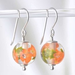 Elegant drop earrings featuring apricot glass flowers in a vibrant, colorful design. The round glass beads have a unique floral pattern that adds a touch of nature-inspired style.