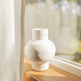 A round, tall white ceramic vase with a simple, minimalist design.
