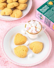 Shortbread spritz cookies, round and golden in color, with a delicate texture and a light, buttery flavor. Packaged in a green box with floral designs.