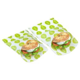 Two reusable vegan beeswax food wraps with a sandwich made of whole grain bread, vegetables, and a plant-based patty.